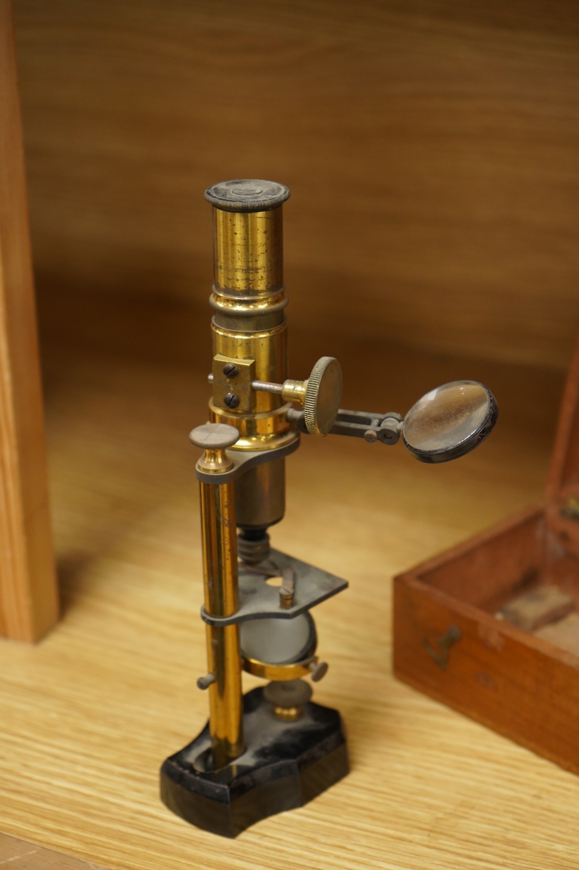 A late 19th/early 20th century French brass compound monocular microscope, height 20.5cms, together with a teak case; 23cm wide, 9cm deep, 7cm high